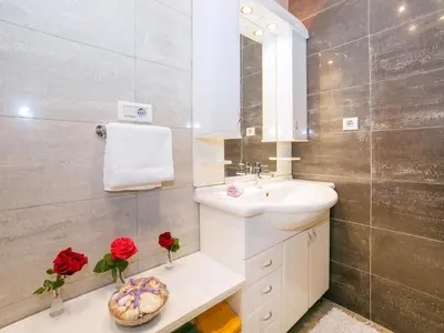a bathroom with a sink and a mirror and red roses at Villa Royal Dream in Sveti Stefan