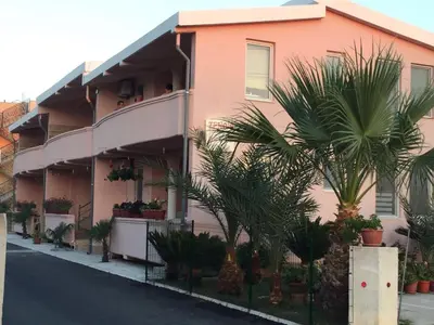 a pink building with palm trees in front of it at Family Apartments Pepic in Ulcinj