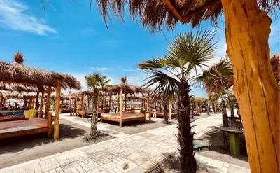 a resort with palm trees and tables and umbrellas at Family Apartments Pepic in Ulcinj
