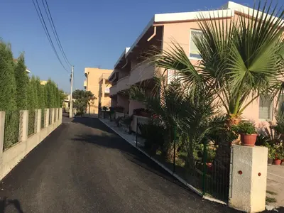 a street with a fence and palm trees next to a house at Family Apartments Pepic in Ulcinj