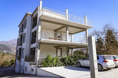 a building with a balcony and a car parked in a parking lot at Apartman Zorana in Tivat