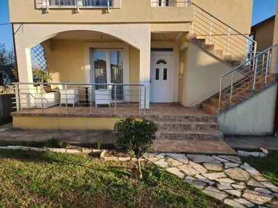 a house with stairs leading to a white door at Apartments Donja Gorica in Podgorica
