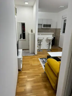 a living room with a yellow couch and a kitchen at N&J apartman in Podgorica