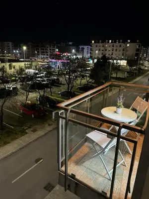 a table on a balcony with a city at night at N&J apartman in Podgorica