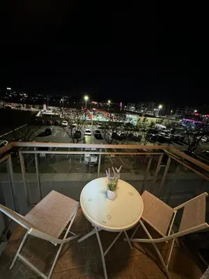 a table and chairs on a balcony at night at N&J apartman in Podgorica