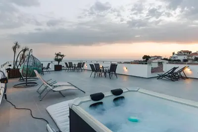 a deck with a hot tub and chairs and the ocean at Casa Bianca 1 in Ulcinj
