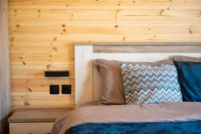 a bedroom with a bed and a wooden wall at RAOS Cottage in Ulcinj