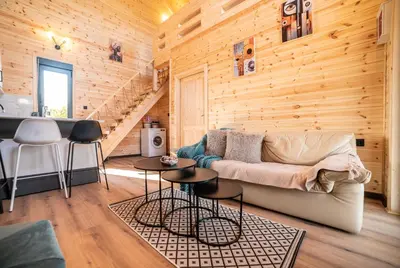 a living room with wooden walls and a couch and tables at RAOS Cottage in Ulcinj