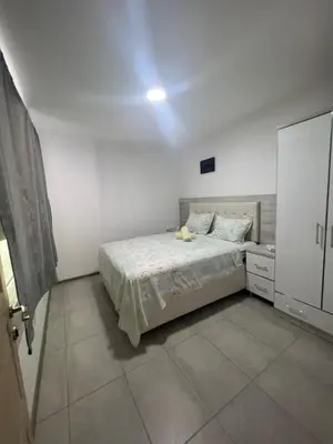 a white bedroom with a bed and a dresser at Apartments DIJAR in Ulcinj