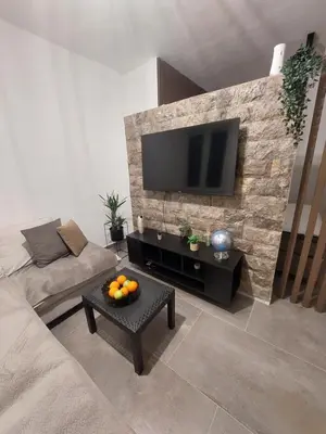 a living room with a flat screen tv on a stone wall at Apartment Wild Beauty in Kotor