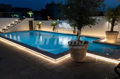a swimming pool at night with a tree in a pot at Vila Kalina Apartments in Sutomore