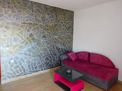a red couch in a room with a stone wall at Apartmani Hamburg 1 in Donji Štoj