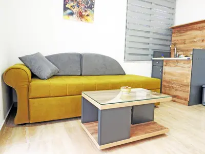 a living room with a yellow couch and a table at Apartmani Hamburg 1 in Donji Štoj