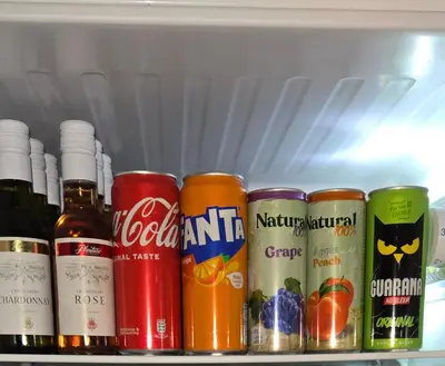 a shelf filled with cans of soda and other drinks at Enjoy Apartmani in Podgorica
