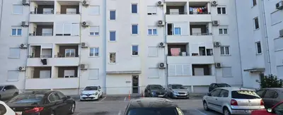 a parking lot with cars parked in front of a tall building at Enjoy Apartmani in Podgorica