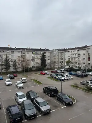 a parking lot with cars parked in front of buildings at Enjoy Apartmani in Podgorica