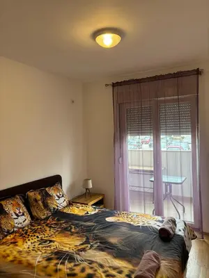 a bedroom with a bed with a leopard print blanket at Enjoy Apartmani in Podgorica