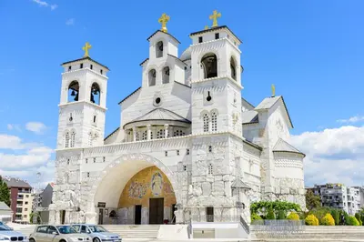 a church with two towers and a car parked in front at HarmonyHome in Podgorica