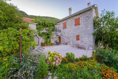 a stone building with a yard with flowers at Mediteraneo Villa in Kaluđerovići