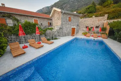 a pool with chairs and umbrellas next to a building at Mediteraneo Villa in Kaluđerovići