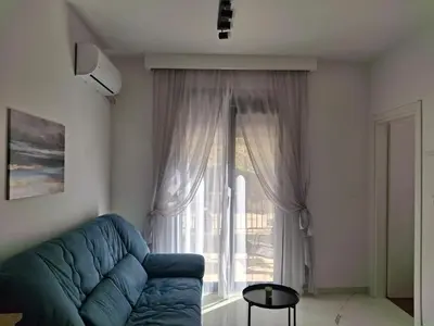 a living room with a blue couch and a large window at Green Harmony in Kotor