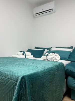 a bed with a green blanket next to a couch at Budva apartman Vasić in Budva