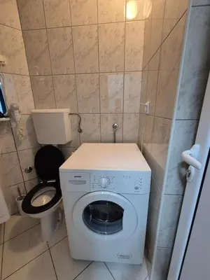a small bathroom with a washing machine and a toilet at Budva apartman Vasić in Budva