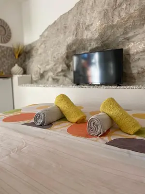 three towels on a bed with a tv in a room at Casa Calda Apartments in Cetinje