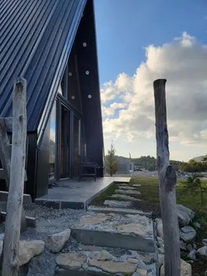 a house with a black roof and some rocks at Cottage MATEJ in Podgorica