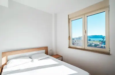 a white bedroom with a bed and a window at Sea-view PD38 by In Property in Budva