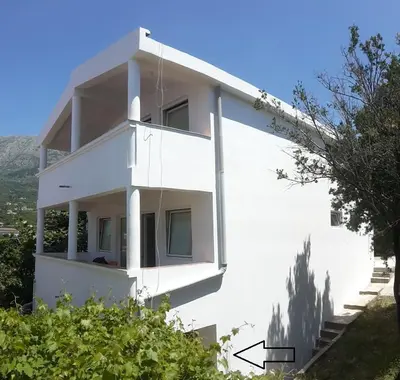 a white apartment building with a view of a tree at Dzenan apartmani in Dobra Voda