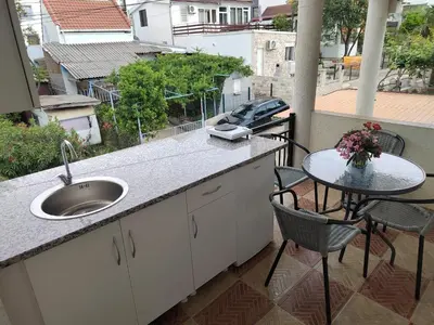 a kitchen with a sink and a table on a balcony at Dzenan apartmani in Dobra Voda