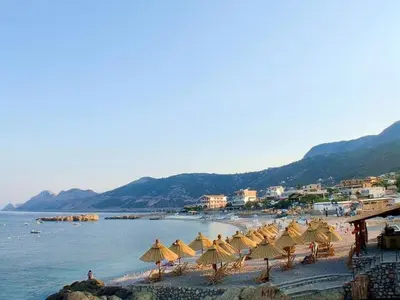 a group of umbrellas on a beach with the water at Dzenan apartmani in Dobra Voda