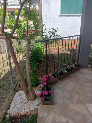 a garden with a tree and flowers next to a fence at Dubrava 112 in Dobra Voda