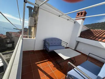 a balcony with a blue chair and a table at Apartman Horizont in Petrovac na Moru