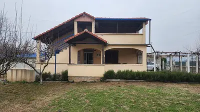 a white house with a yard in front of it at Lush Garden Villa Close to Airport with Hi-Speed Wifi in Podgorica