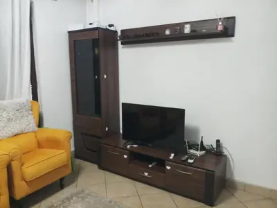 a living room with a tv and a chair at Lush Garden Villa Close to Airport with Hi-Speed Wifi in Podgorica