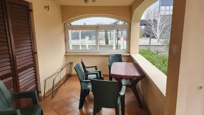 a small balcony with chairs and a table and a window at Lush Garden Villa Close to Airport with Hi-Speed Wifi in Podgorica