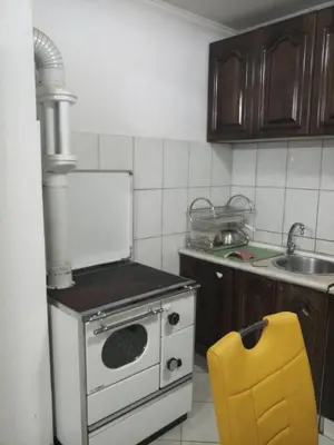 a kitchen with a stove and a yellow chair at Lush Garden Villa Close to Airport with Hi-Speed Wifi in Podgorica