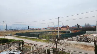 a view of a road with a fence and houses at Lush Garden Villa Close to Airport with Hi-Speed Wifi in Podgorica