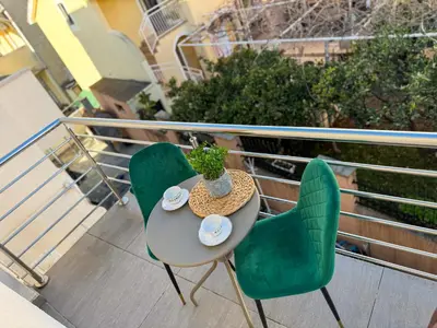 a table and two green chairs on a balcony at Villa Sun Budva in Budva
