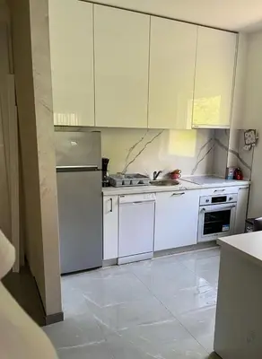 a kitchen with white cabinets and a refrigerator at Sky apartment - Becici in Becici