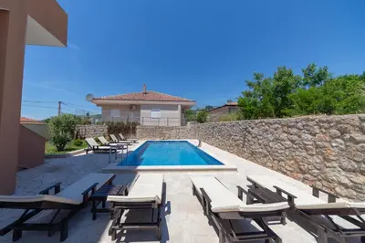 a swimming pool with lounge chairs and a stone wall at Villa Bojana in Neodi