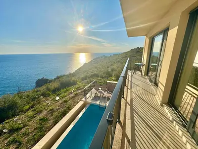 a house with a balcony with a swimming pool at Apartments Azimut Rezevici in Budva