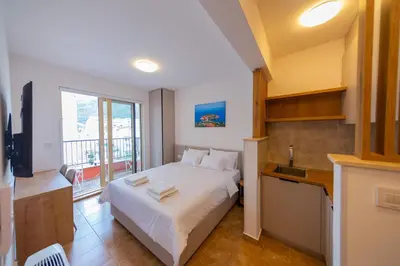 a bedroom with a white bed and a balcony at Luča Apartments in Budva