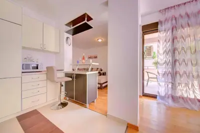 a kitchen with a table and a chair in a room at Sea Point apartment Korda in Budva