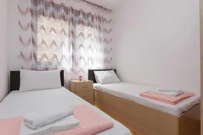 two beds in a room with pink and white walls at Sea Point apartment Korda in Budva