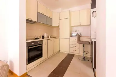 a kitchen with white cabinets and a chair in it at Sea Point apartment Korda in Budva