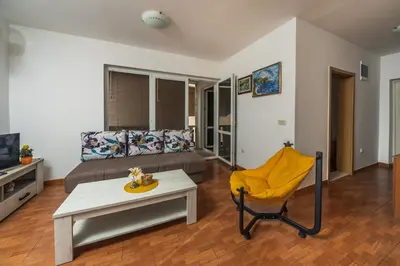a living room with a bed and a table and a yellow chair at Apartments Franićević in Petrovac na Moru