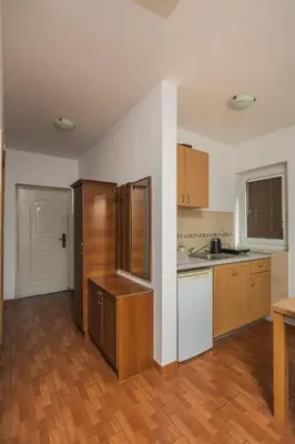 an empty kitchen with wooden cabinets and a table at Apartments Franićević in Petrovac na Moru